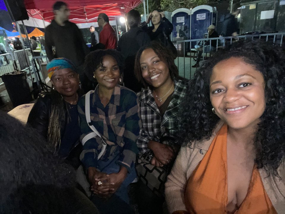 Four From Queens, With Love members smiling together for a selfie at an outdoor gathering.