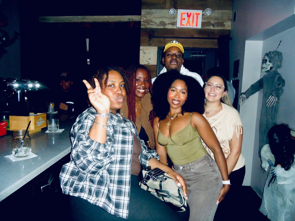 From Queens, With Love members posing together inside a neighborhood gathering space.